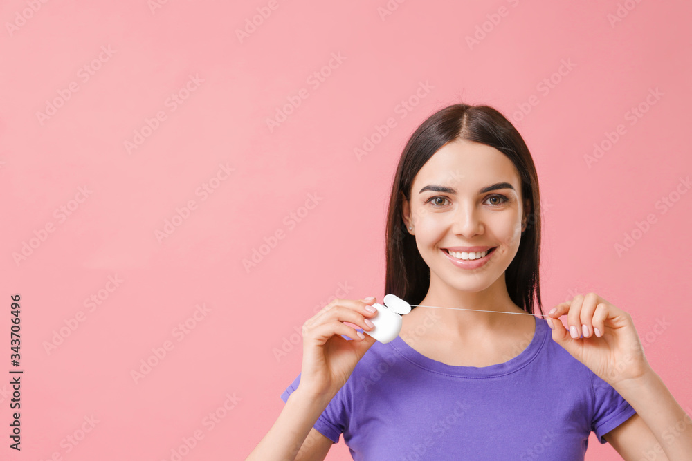 Beautiful young woman with dental floss on color background