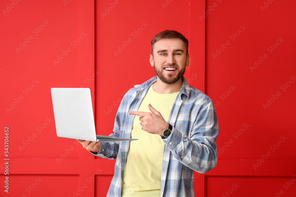 Male programmer with laptop on color background