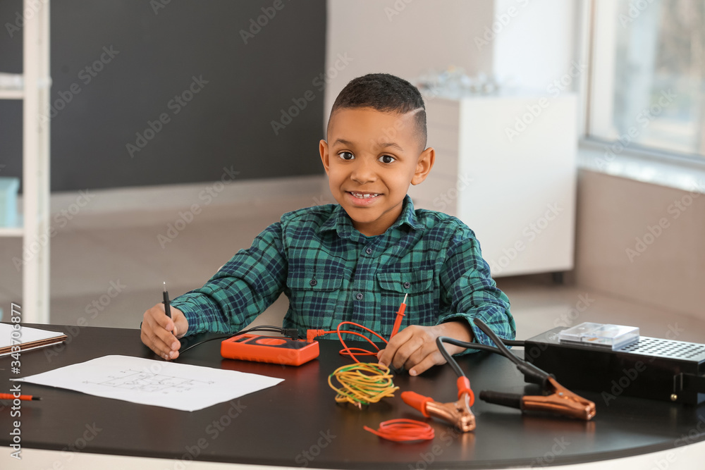 Little African-American electrician at table in room