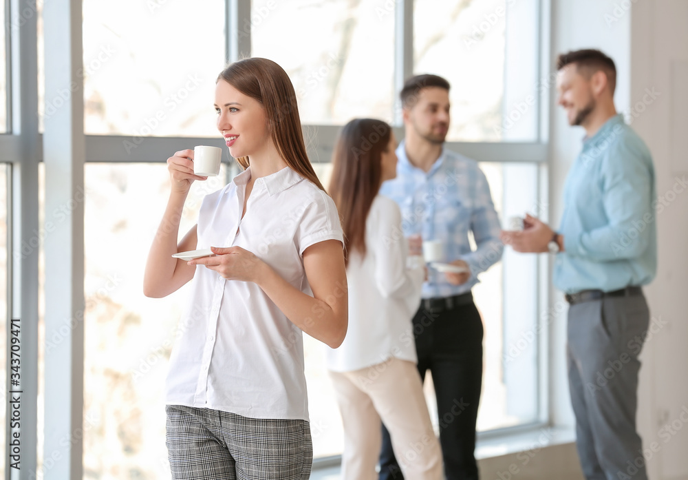 Young businesswoman drinking coffee in office