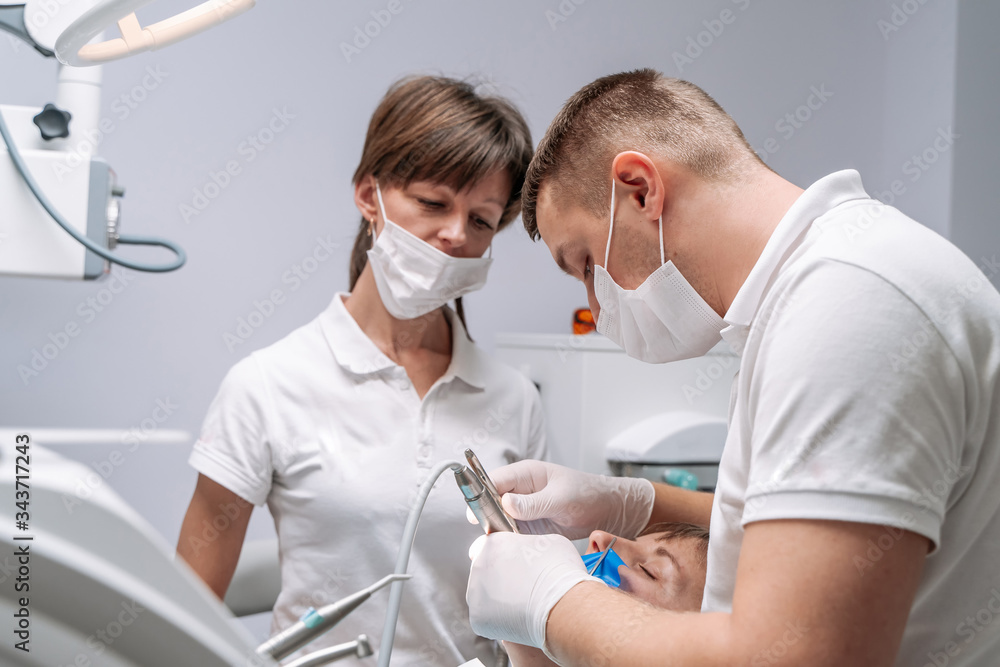 Professional dentist and nurse doing operation on female patient. A team of dentists with client in 