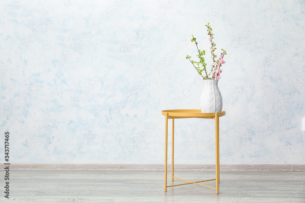 Vase with beautiful blooming branches on table in room