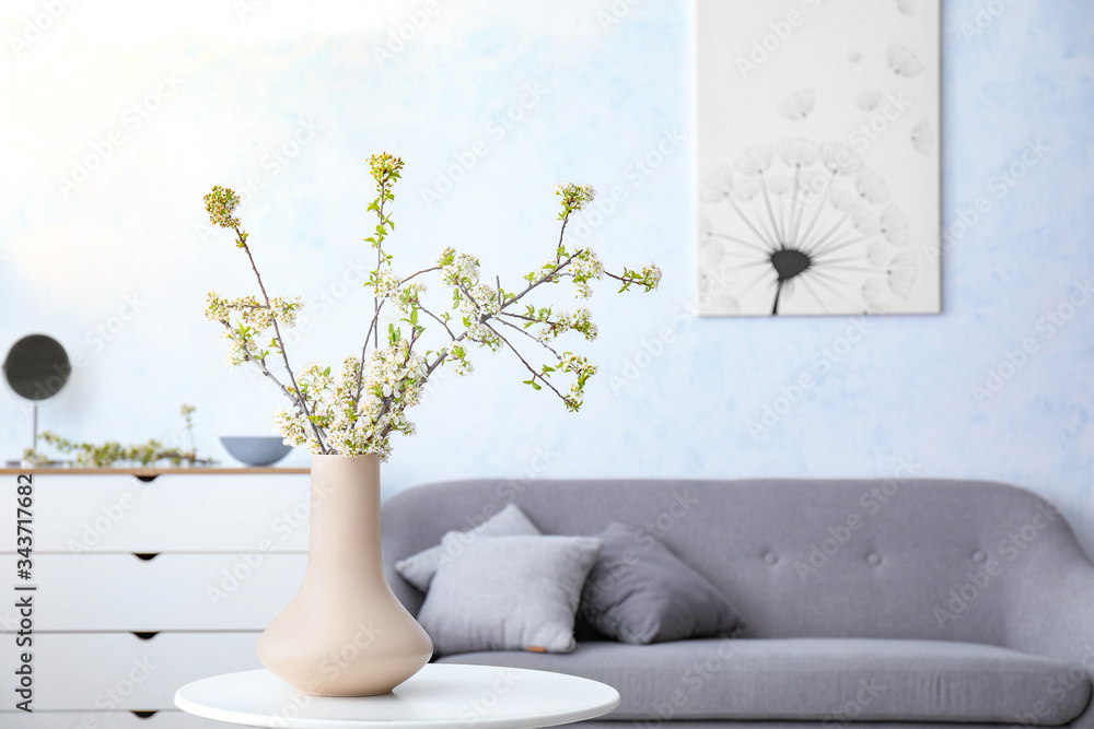 Vase with beautiful blooming branches on table in room