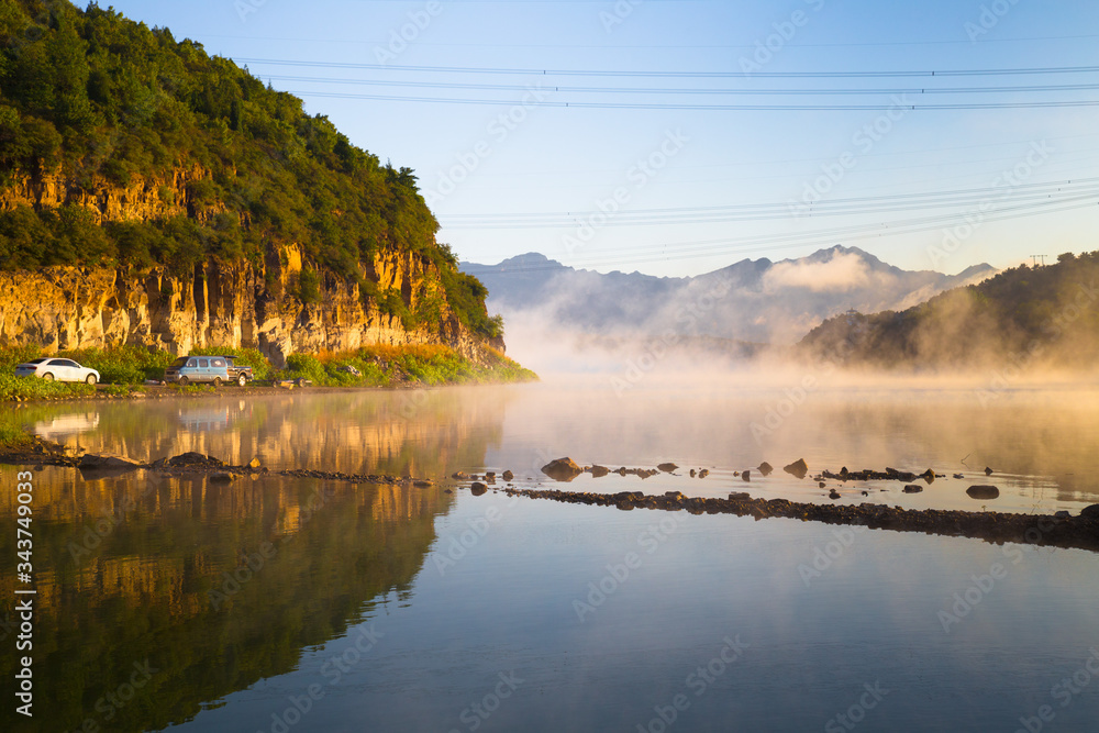 Concept road trip: misty lake with mountain reflection in the morning