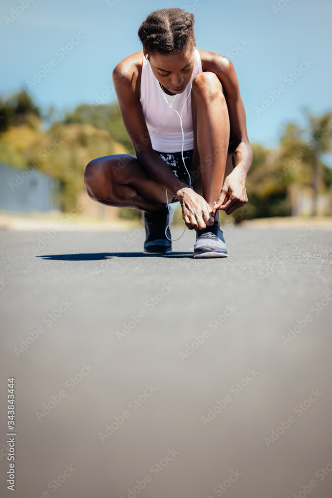 Woman on morning run fastening her shoe laces.