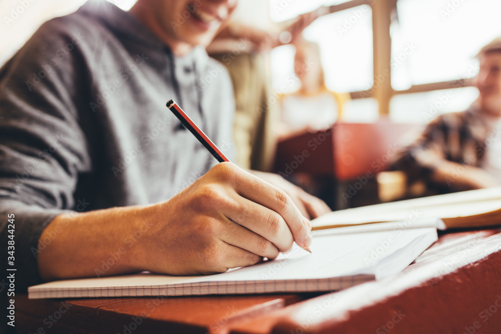 Student taking notes sitting at desk during lecture