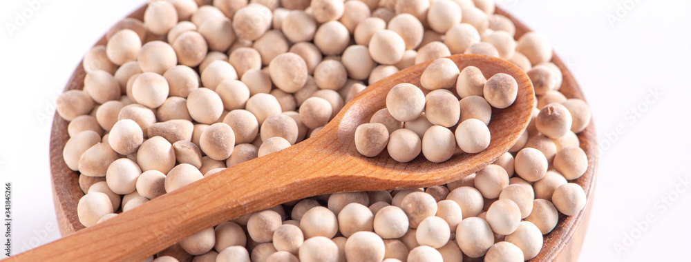 Dry raw brown tapioca pearls in a wooden bowl with spoon isolated on white background, close up, ing