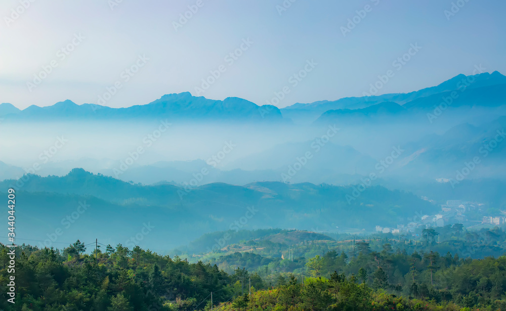 Mountain range with visible silhouettes through the morning colorful fog.