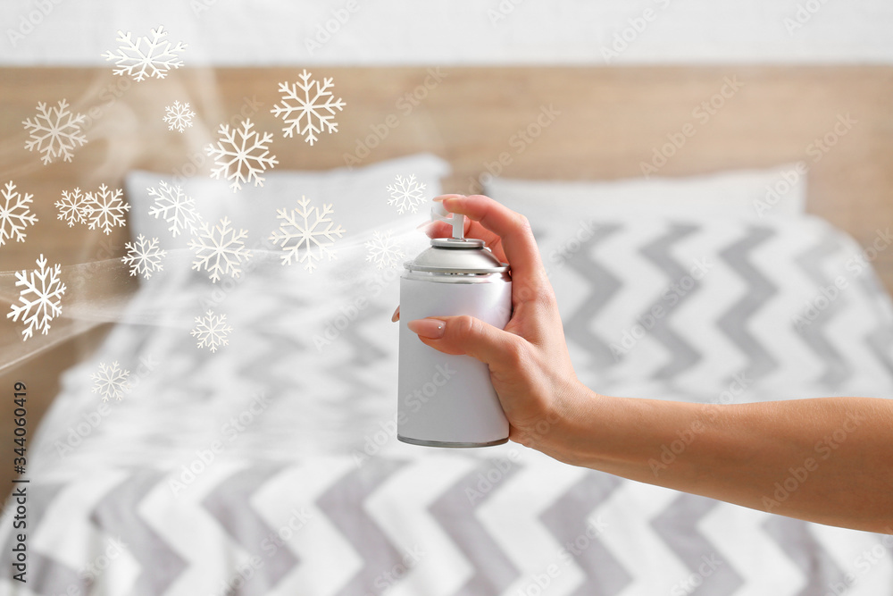 Woman spraying air freshener at home