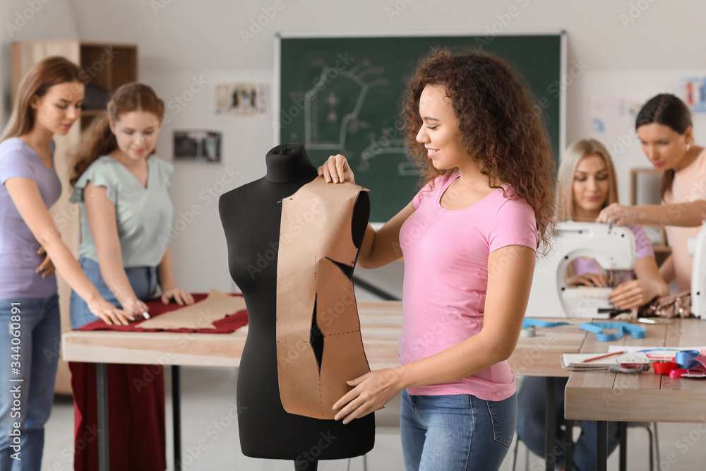 Young woman near mannequin during tailors class in atelier