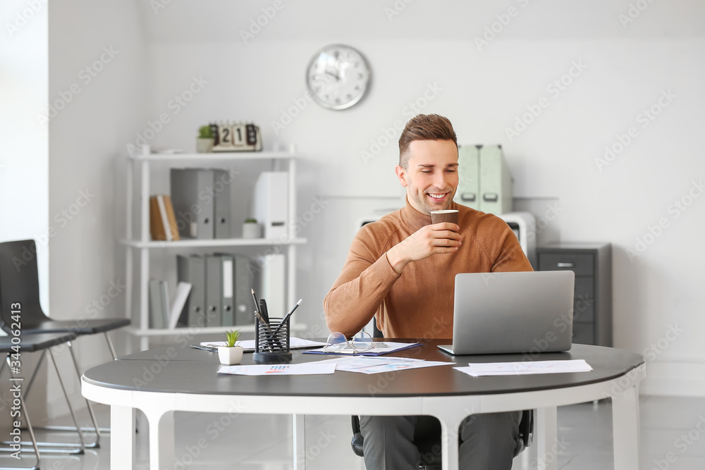 Young man drinking coffee while working in office