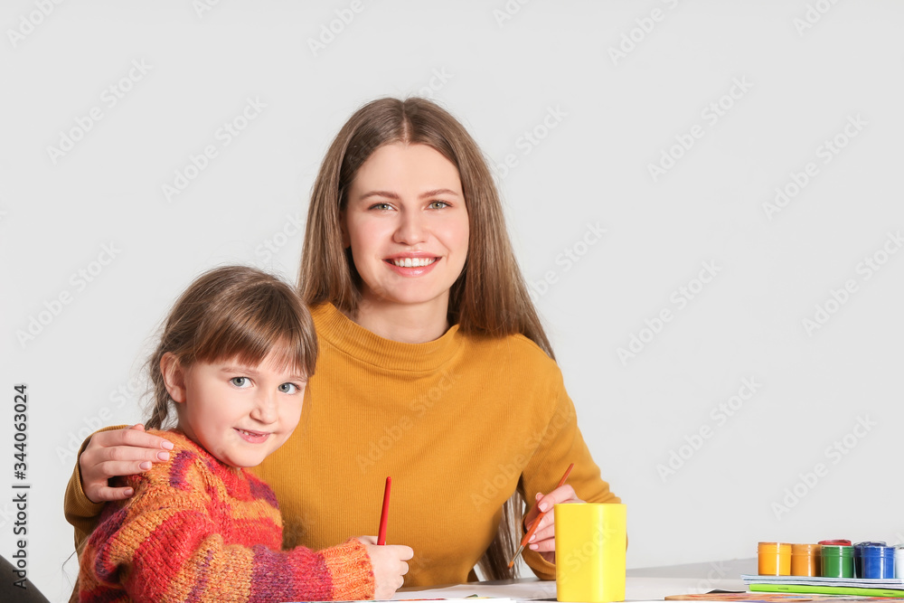 绘画老师在灯光背景下给小女孩上私人艺术课