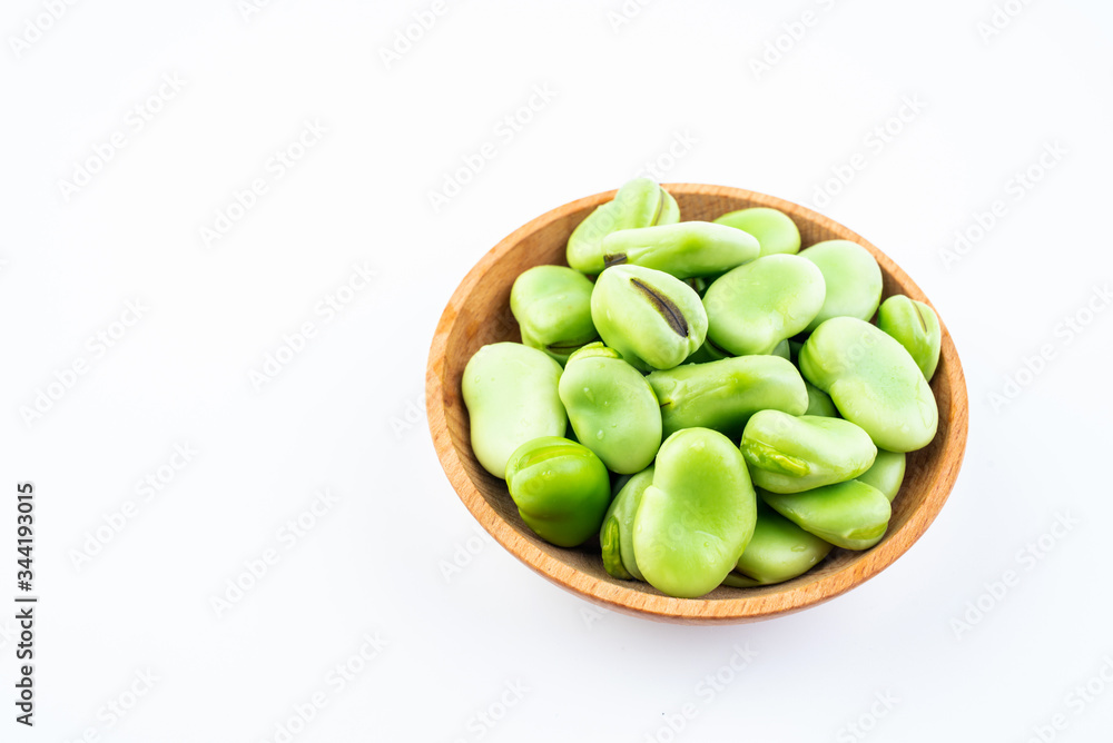 Fresh broad beans in a saucer on white background