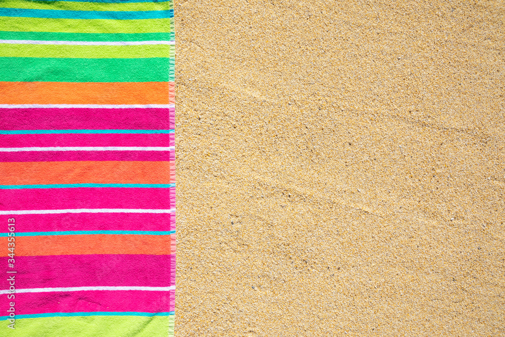 Beach towel photographed from above on sandy beach with copy space, hot summer day, vacation destina