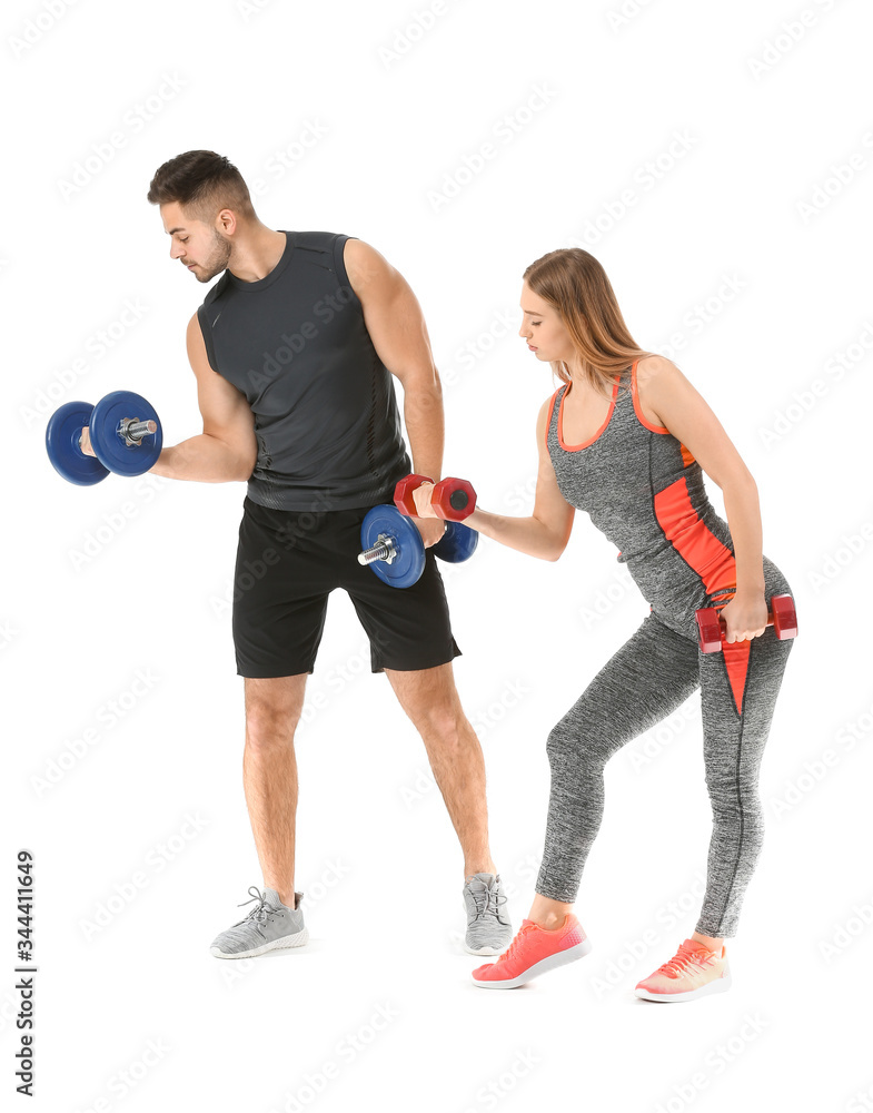 Sporty young couple training with dumbbells on white background