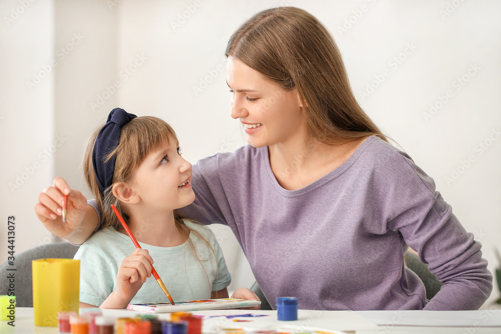 Drawing teacher giving private art lessons to little girl at home