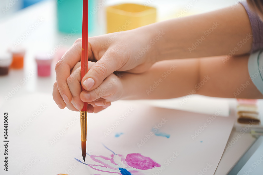 Drawing teacher giving private art lessons to little girl at home, closeup