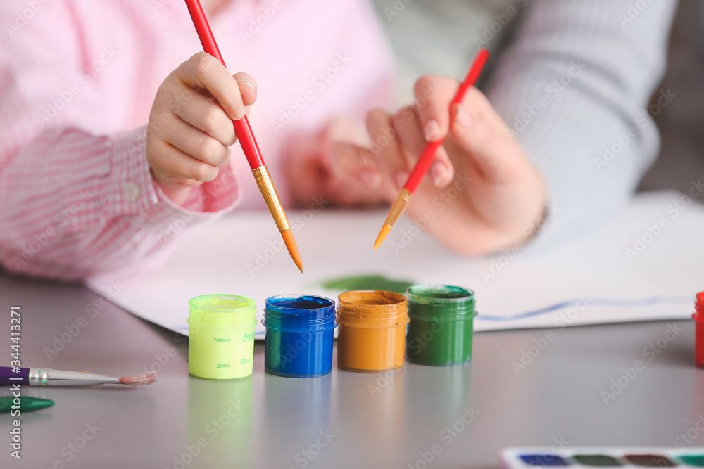 Drawing teacher giving private art lessons to little girl at home, closeup