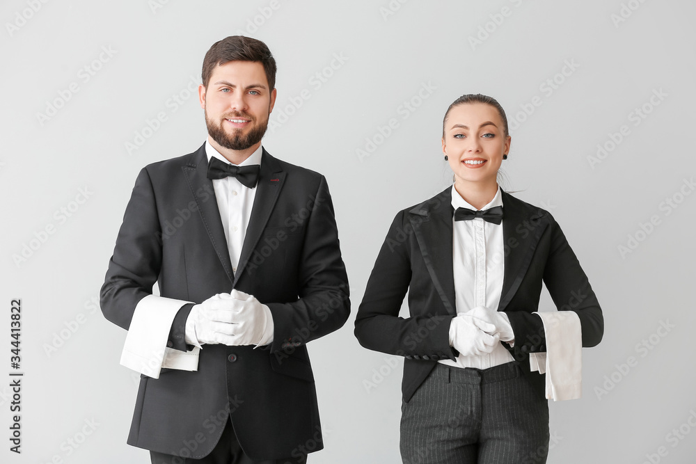 Male and female waiters on grey background