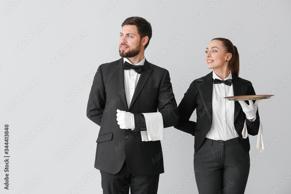 Male and female waiters on grey background