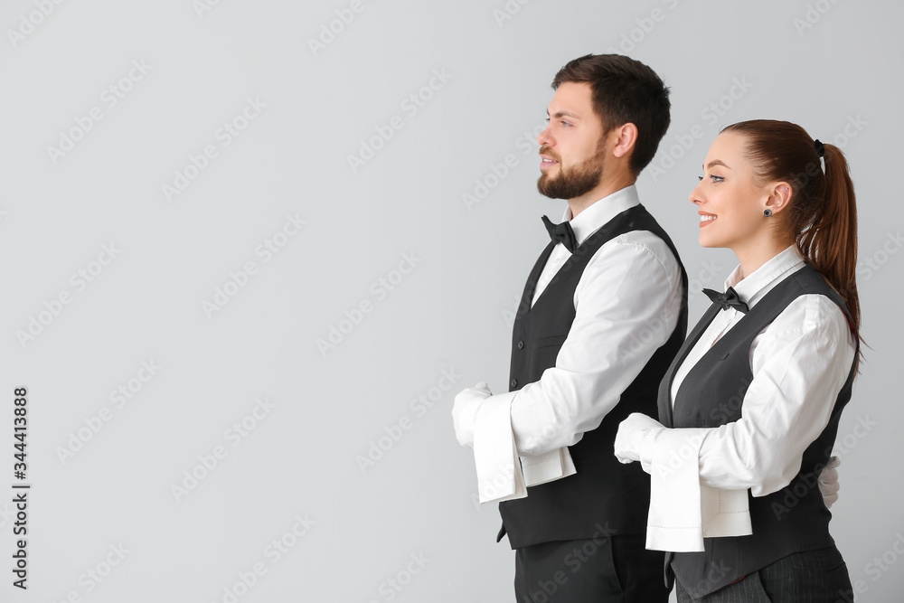 Male and female waiters on grey background