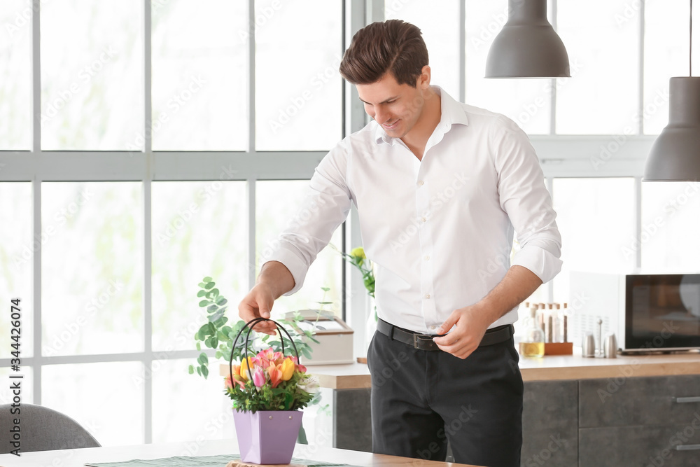 Handsome man putting bouquet of flowers on table