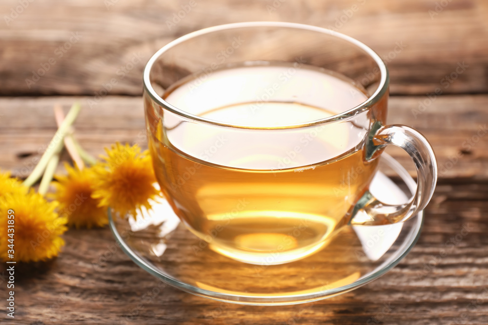 Cup of healthy dandelion tea on wooden background