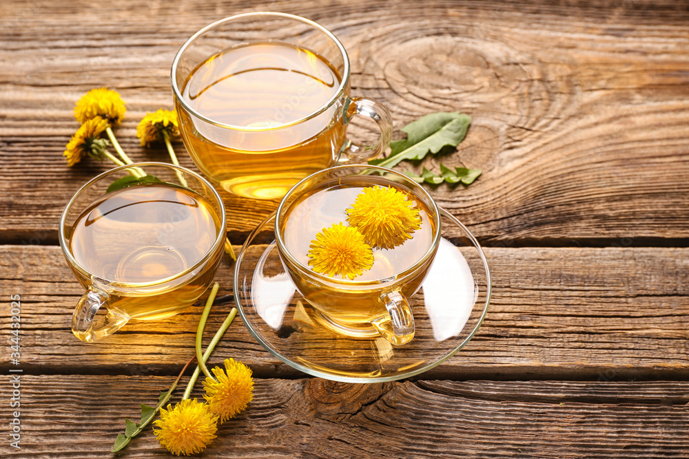 Cups of healthy dandelion tea on wooden background