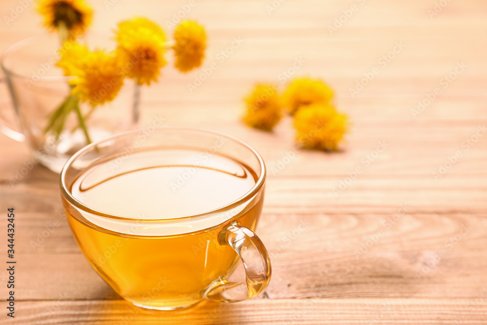 Cup of healthy dandelion tea on wooden background