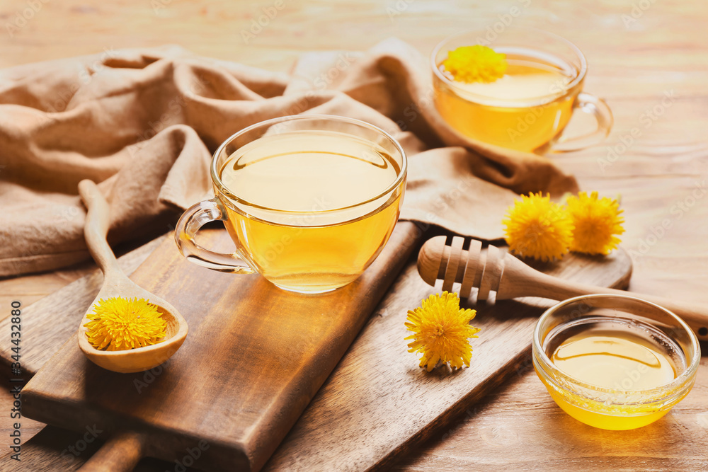 Cup of healthy dandelion tea with honey on table