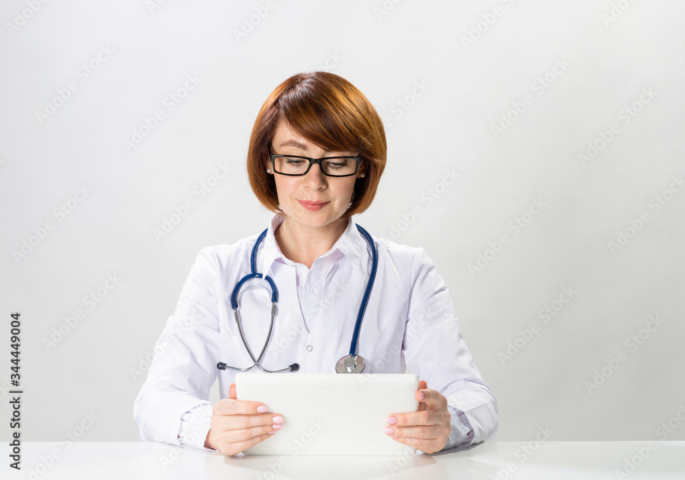 Redhead doctor using tablet computer in office