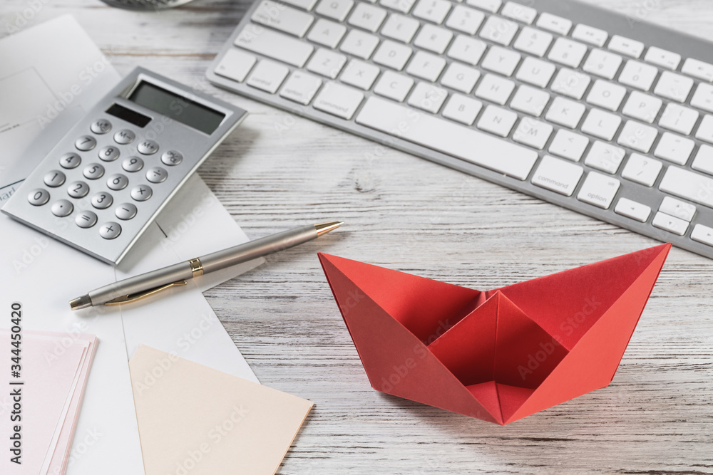 Businessman workspace at desk with red paper ship