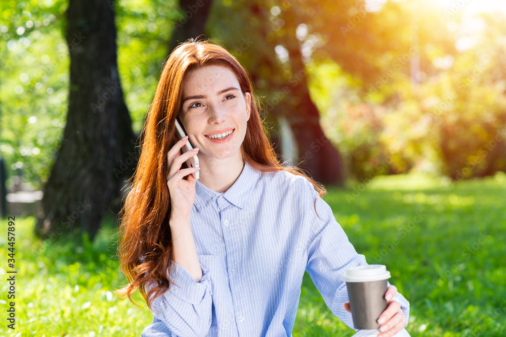 Young redhead woman talking on smartphone