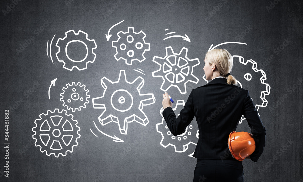 Businesswoman draws gears mechanism on blackboard