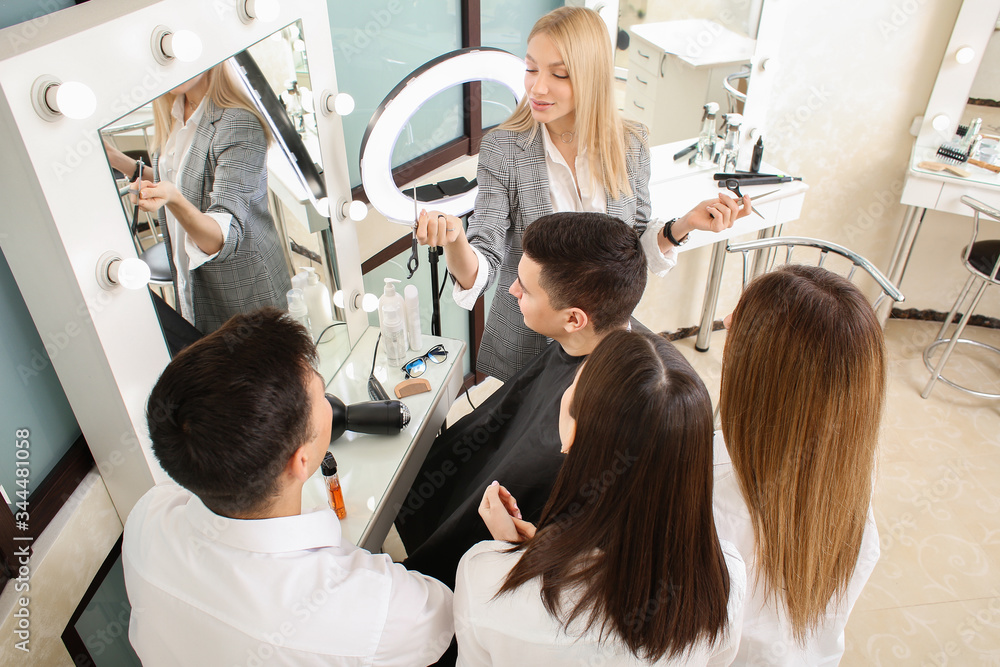 Professional hairdresser teaching young people in salon