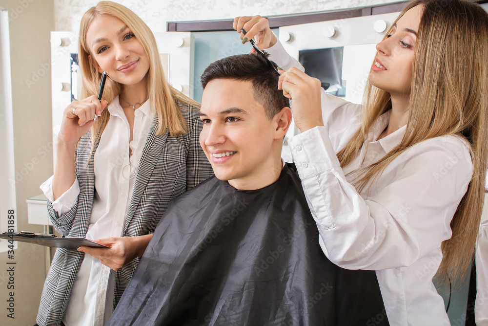 Young woman with professional hairdresser and model during courses in salon