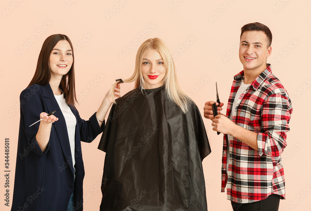 Young hairdressers working with client against color background