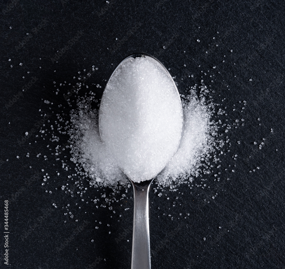 Sugar in a spoon placed on a black background