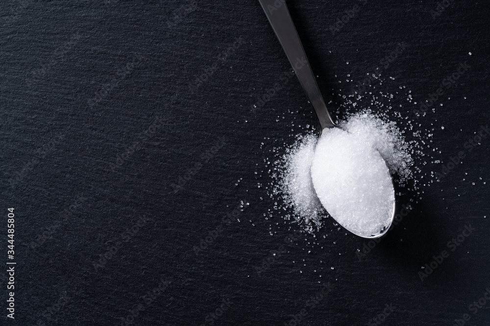 Sugar in a spoon placed on a black background