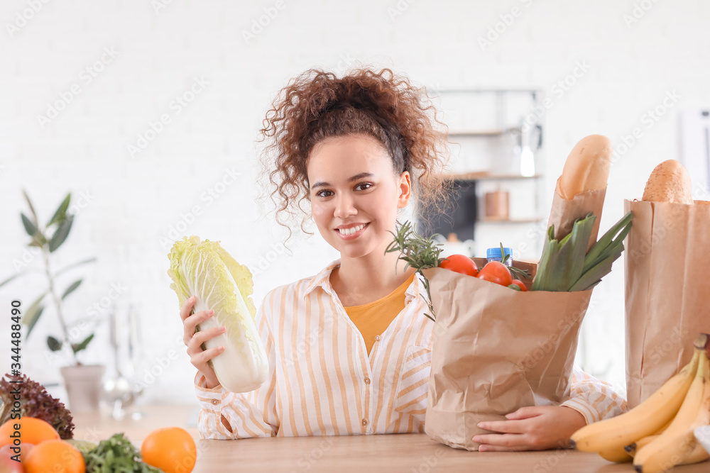 Young woman with fresh products from market at home