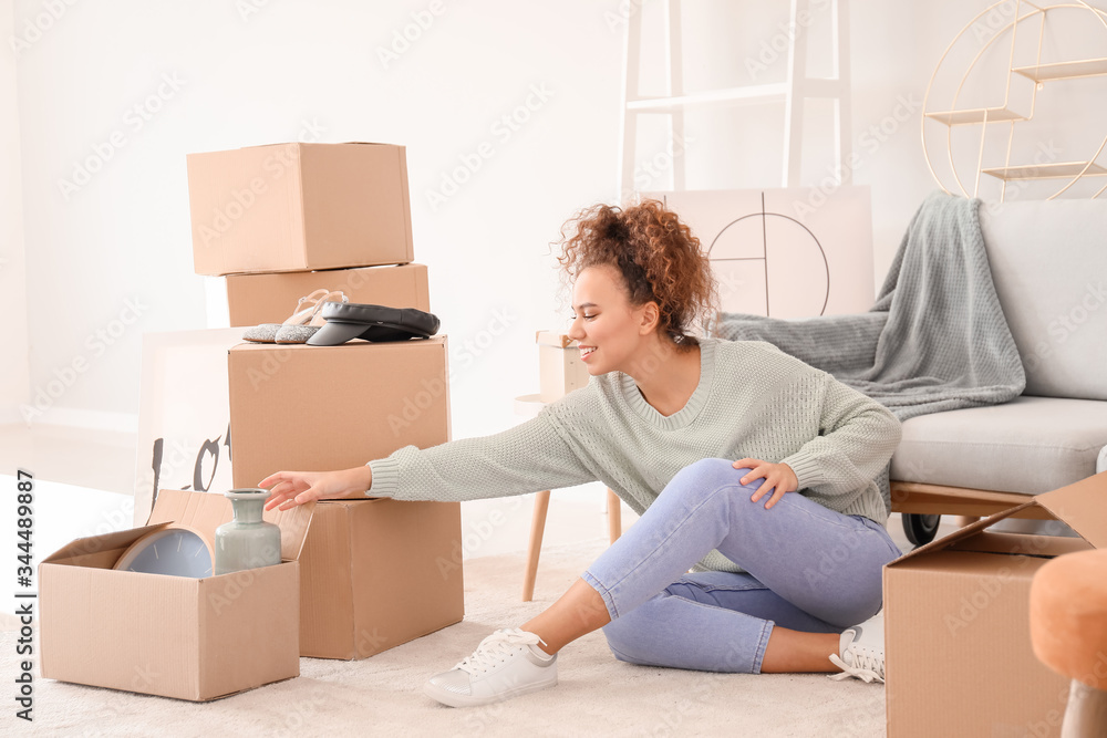 Young woman unpacking moving boxes in her new home