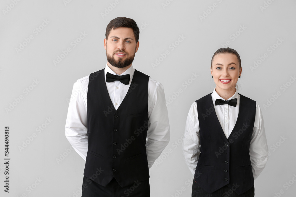 Male and female waiters on grey background