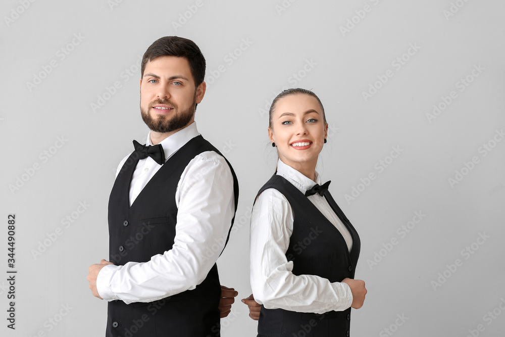 Male and female waiters on grey background