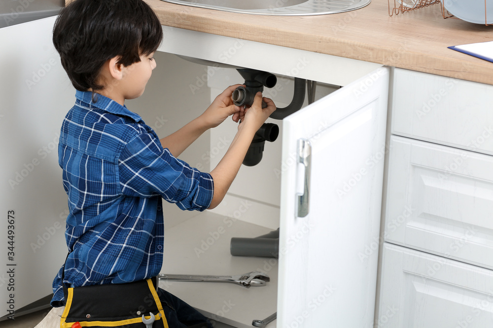 Little plumber repairing sink in kitchen