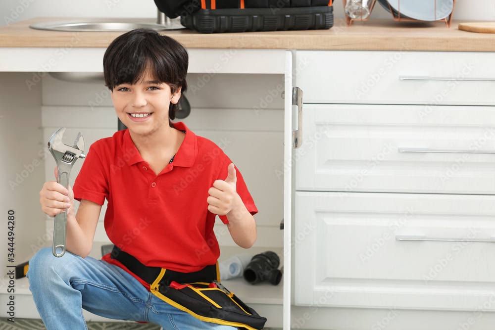 Portrait of little plumber in kitchen