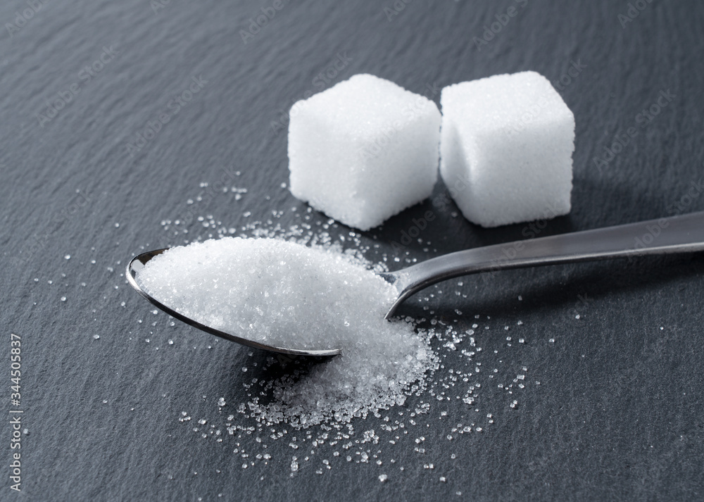 Sugar in a spoon placed on a black background