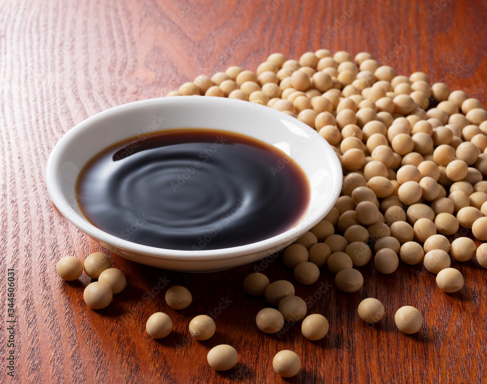 Soy sauce in a plate and soybeans scattered around