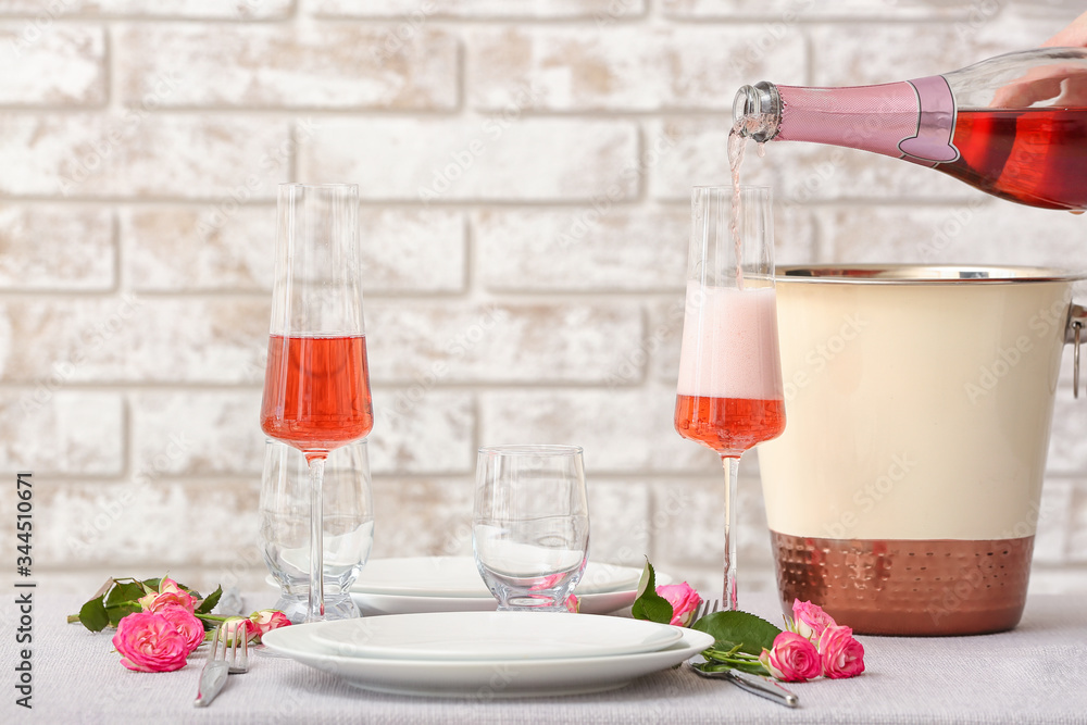 Pouring of champagne from bottle into glass on table