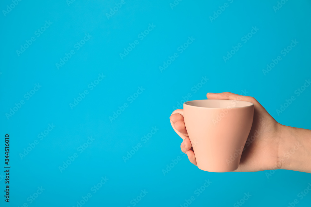 Female hand with blank cup on color background