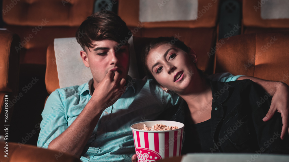 Loving couple man and woman watch a boring movie and yawning at the cinema chair